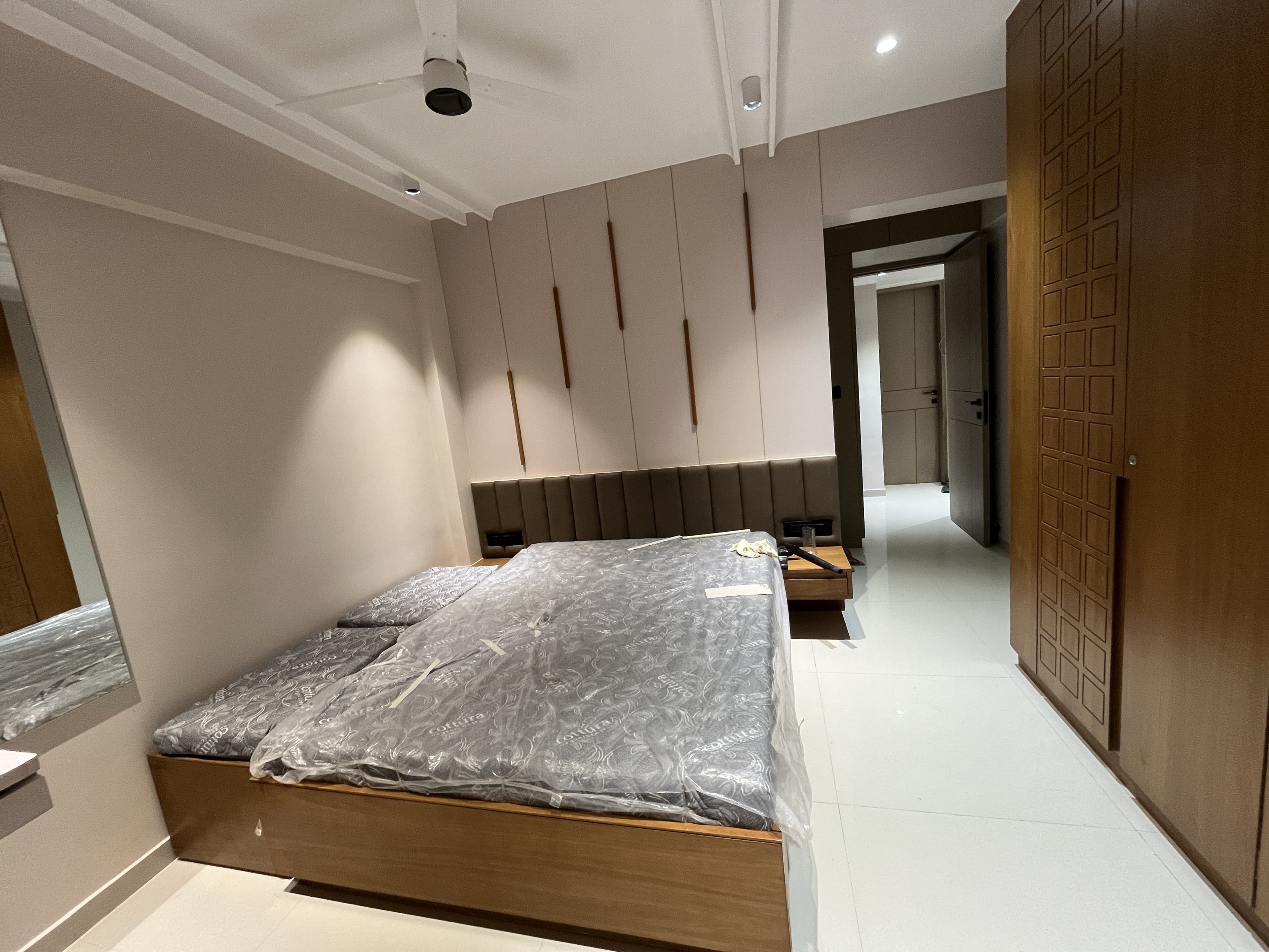Master bedroom with cushioned headboard, fluted wardrobe doors and recessed lighting by BR Interiors